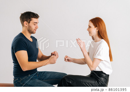 Studio shot of happy young man and woman playing rock scissors paper game on white isolated background. Concept of resolving conflicts in a peaceful and ecological way. Studio shot of happy young man and woman playing rock scissors paper game on white isolated background. Concept of resolving conflicts in a peaceful and ecological way. 86101395