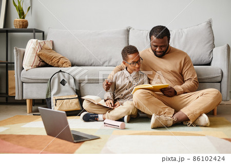 Father and Son Reading Book on Floor Father and Son Reading Book on Floor 86102424