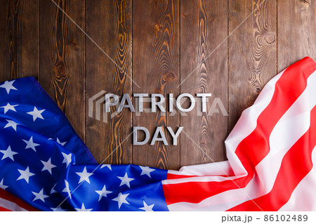 the words patriot day laid with silver metal letters on wooden board surface with crumpled usa flag 86102489