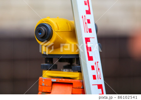 close-up view of cheap geodesy level device with tower ruler outdoors 86102541