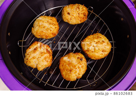 cooked chicken meatballs on steel grille in opened airfryer 86102683