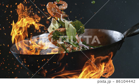 Freeze Motion of Wok Pan and Flying Ingredients in the Air. Freeze Motion of Wok Pan and Flying Ingredients in the Air. 86104442