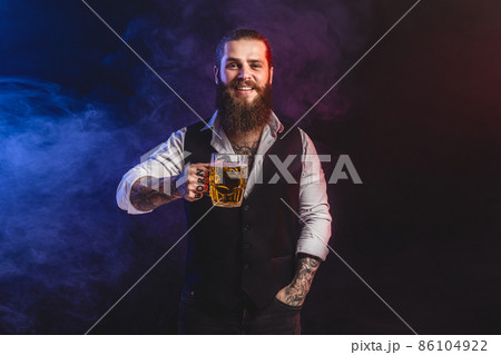 Smilling bearded man holds tasty draft beer in hand. Drinking, October fest concept. Smilling bearded man holds tasty draft beer in hand. Drinking, October fest concept. 86104922