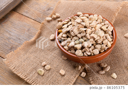 Dry raw cicerchia or indian pea on a clay plate with napkin on natural wooden background, close up. Dry raw cicerchia or indian pea on a clay plate with napkin on natural wooden background, close up. 86105375