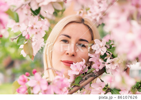 Young woman among the blossoming trees. Spring nature park or garden, flowering trees. Concept spring woman health Young woman among the blossoming trees. Spring nature park or garden, flowering trees. Concept spring woman health 86107626
