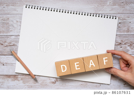 「DEAF」と書かれた積み木とペン、ノート、人の手 86107631
