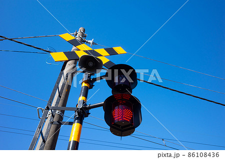 点滅中の踏切の警報機 見上げる青空 86108436