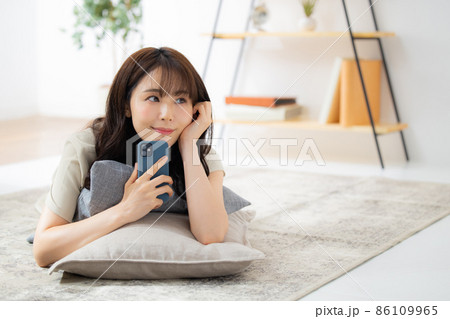 リビングでスマホを見る女性　 86109965