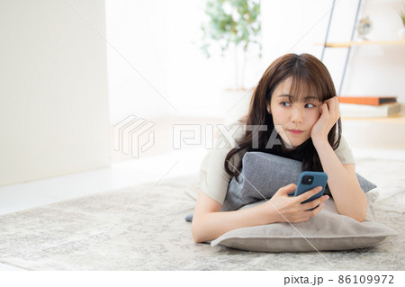 リビングでスマホを見る女性　 86109972