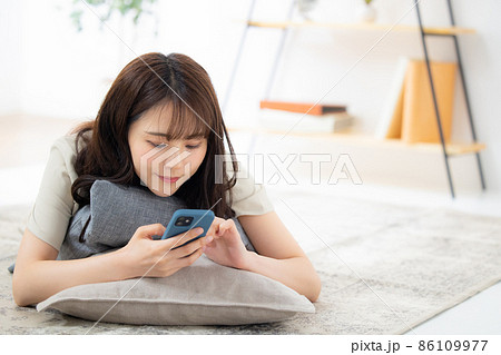 リビングでスマホを見る女性　 86109977