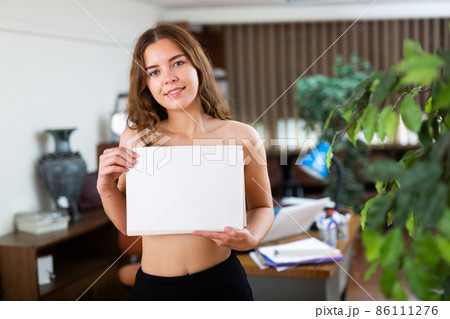 Nude girl covers her breasts with ream of paper in company office 86111276