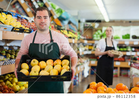 Salesman holding box of fresh apples during work on the supermarket 86112358