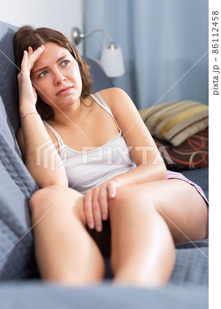 Upset girl sitting on sofa at home 86112458