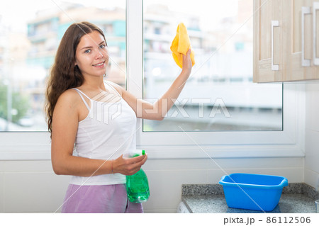 Young positive woman doing chores cleaning window 86112506
