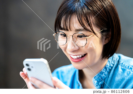スマホを使う眼鏡の若い女性 86112606