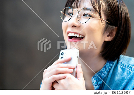 スマホを使う眼鏡の若い女性 スマホを使う眼鏡の若い女性 86112607