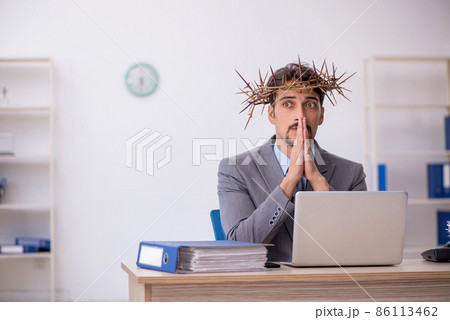 Young male employee wearing prickly wreath on head Young male employee wearing prickly wreath on head 86113462
