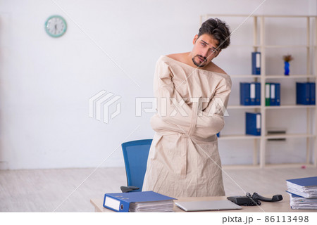 Crazy young man in straitjacket at the office Crazy young man in straitjacket at the office 86113498