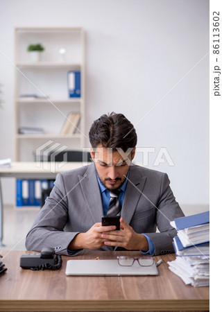 Young male employee unhappy with excessive work in the office Young male employee unhappy with excessive work in the office 86113602