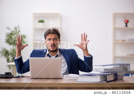 Young male employee unhappy with excessive work in the office 86113608