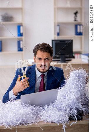 Young male employee and a lot of cut papers in the office 86114307