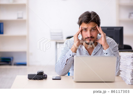 Young male employee and too much work in the office 86117303