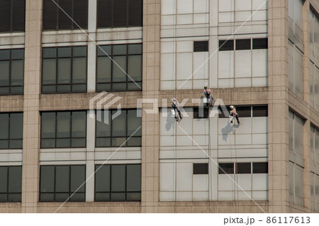Group of workers cleaning windows service on high rise office building. 86117613