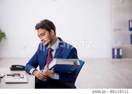 Young male employee unhappy with excessive work in the office Young male employee unhappy with excessive work in the office 86118111
