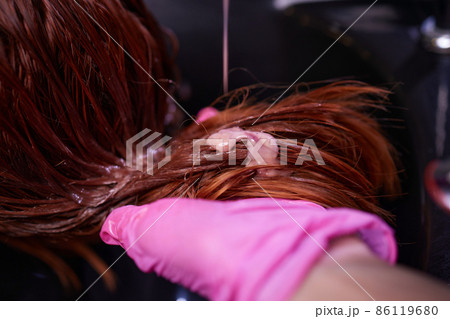 Hairdresser in beauty salon washes his client hair, before procedure of applying natural restoring ingredients and vitamins to hair and haircut. Hairdresser in beauty salon washes his client hair, before procedure of applying natural restoring ingredients and vitamins to hair and haircut. 86119680