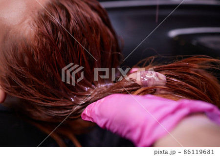 Hairdresser in beauty salon washes his client hair, before procedure of applying natural restoring ingredients and vitamins to hair and haircut. Hairdresser in beauty salon washes his client hair, before procedure of applying natural restoring ingredients and vitamins to hair and haircut. 86119681