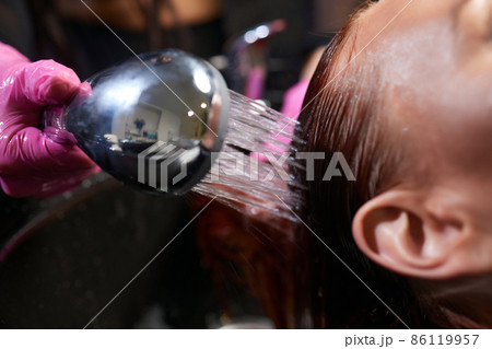 Hairdresser in beauty salon washes his client hair, before procedure of applying natural restoring ingredients and vitamins to hair and haircut. Hairdresser in beauty salon washes his client hair, before procedure of applying natural restoring ingredients and vitamins to hair and haircut. 86119957