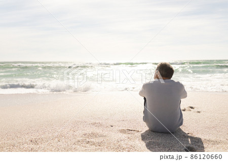 Rear view of biracial senior man looking at horizon over sea from beach shore during sunny day 86120660
