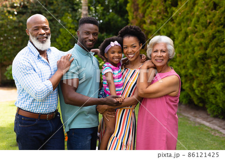 Portrait of smiling three generational african american family standing together at garden 86121425