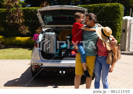 Caucasian family standing near their car smiling looking at each others Caucasian family standing near their car smiling looking at each others 86121550