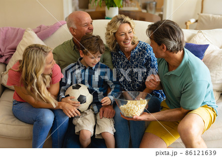 Caucasian three generation family watching tv together on the couch at home Caucasian three generation family watching tv together on the couch at home 86121639