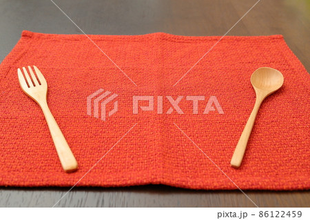 赤色のランチョンマットと木製のスプーンとフォーク 86122459