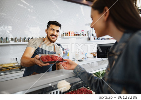 Butcher's shop seller helps to choose product to woman customer 86123288