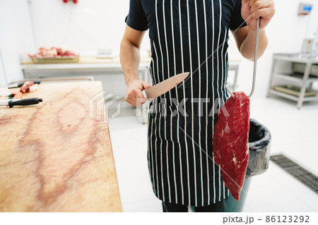 Butcher man holding meat on hook to cut and sell it 86123292