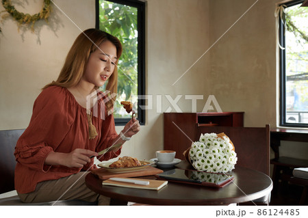 Woman Eating Breakfast in Cafe 86124485