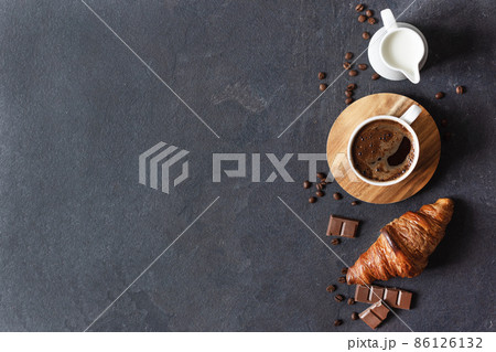 Coffee cup, milk and croissant on black background top view. Coffee cup, milk and croissant on black background top view. 86126132