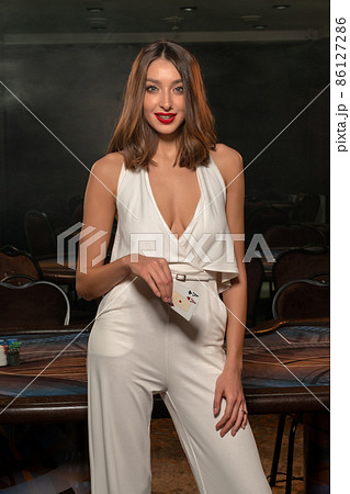 Confident smiling young woman with cards in hands standing in casino Confident smiling young woman with cards in hands standing in casino 86127286