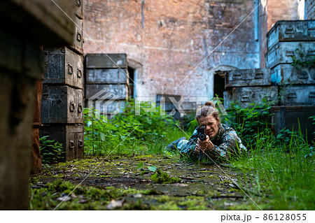 young woman in action while playing paintball young woman in action while playing paintball 86128055