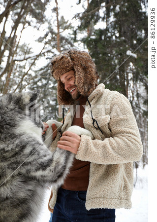 Men playing with siberian husky in winter forest and park, animals and ecology. Pet lover. Dog - human s friend concept Men playing with siberian husky in winter forest and park, animals and ecology. Pet lover. Dog - human s friend concept 86129936