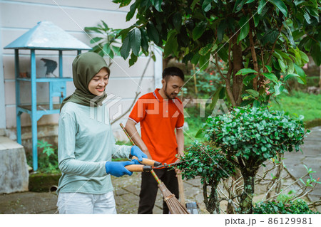 Veiled mother uses plant shears to trim the leaves 86129981