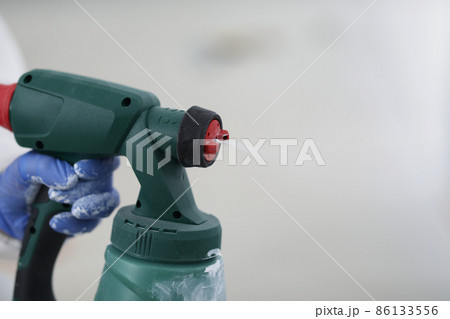 Spray gun in the hands of a builder, close-up 86133556