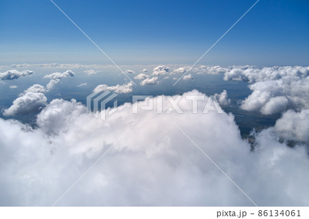 Aerial view from airplane window at high altitude of earth covered with white puffy cumulus clouds. 86134061