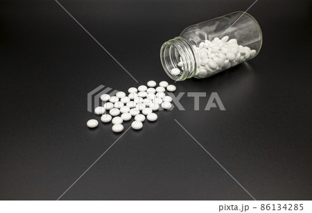 薬瓶からこぼれた白い錠剤/黒背景 White tablets on black paper 薬瓶からこぼれた白い錠剤/黒背景 White tablets on black paper 86134285