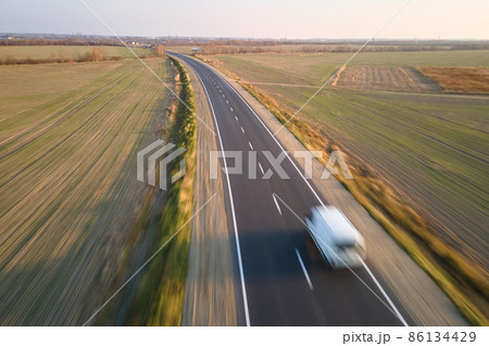 Aerial view of blurred fast moving cargo van driving on highway hauling goods. Delivery transportation and logistics concept 86134429