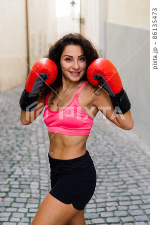 A woman boxer training outdoor - city and nature in background A woman boxer training outdoor - city and nature in background 86135473
