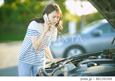 車の故障で電話をする若い女性 車の故障で電話をする若い女性 86136366